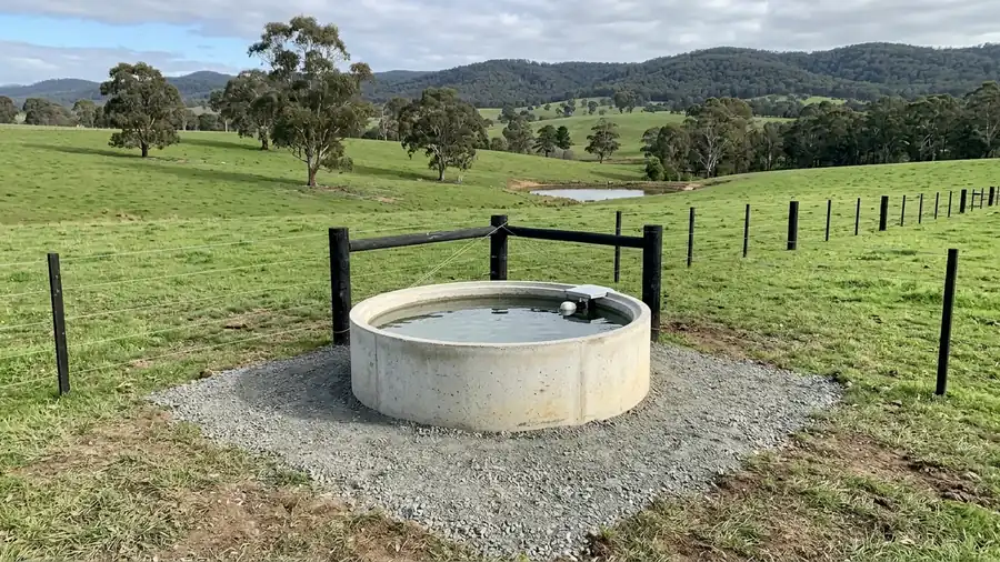 A new stock trough in a fenced corner with a dam behind.